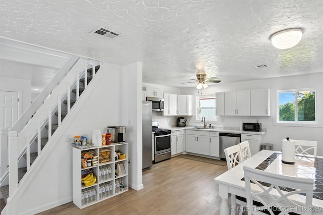27719 S 610th Rd, Bunch, OK 74931 - kitchen featuring appliances with stainless steel finishes, light countertops, light wood-style flooring, white cabinetry, and ceiling fan