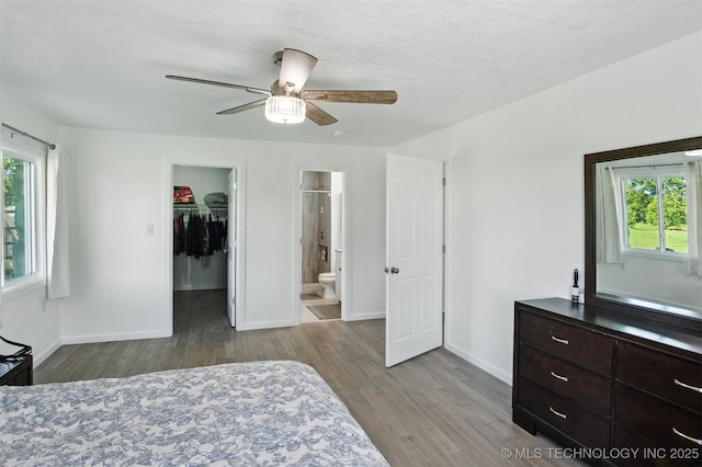 27719 S 610th Rd, Bunch, OK 74931 - bedroom featuring wood finished floors, a walk in closet, multiple windows, a closet, and a textured ceiling