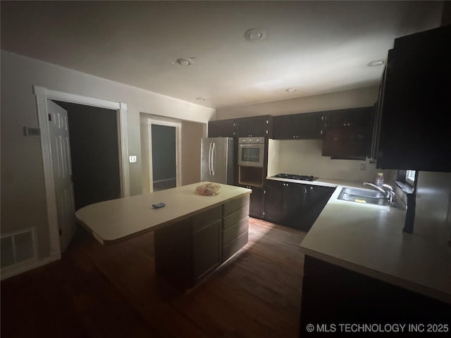 512 S Jules Ave, Cleveland, OK 74020 - kitchen featuring stainless steel appliances, dark wood-style flooring, light countertops, and a center island