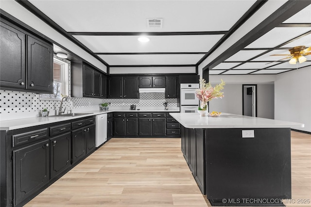 14400 County Road 3490, Ada, OK 74820 - kitchen with dark cabinetry, white appliances, light wood-style flooring, light countertops, and tasteful backsplash