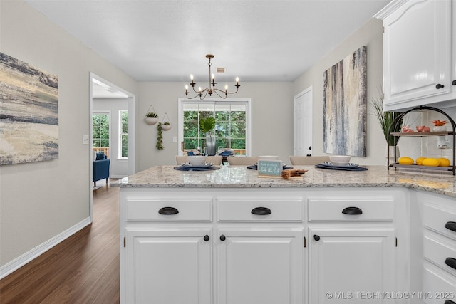 2117 Western Dr, Skiatook, OK 74070 - kitchen featuring dark wood-style flooring, a chandelier, a peninsula, white cabinets, and light stone countertops