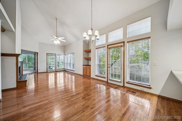 5117 E 89th St, Tulsa, OK 74137 - unfurnished living room with high vaulted ceiling, a ceiling fan, wood-type flooring, a chandelier, and a fireplace