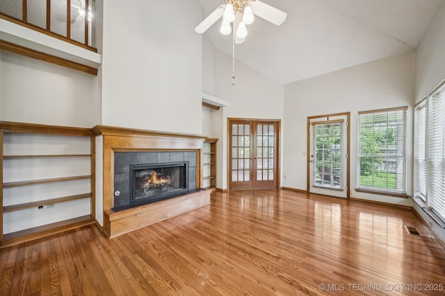 5117 E 89th St, Tulsa, OK 74137 - unfurnished living room featuring wood finished floors, a tiled fireplace, high vaulted ceiling, french doors, and ceiling fan