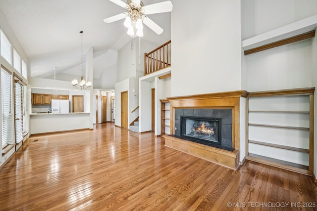 5117 E 89th St, Tulsa, OK 74137 - unfurnished living room featuring a lit fireplace, ceiling fan, light wood-type flooring, a chandelier, and stairs