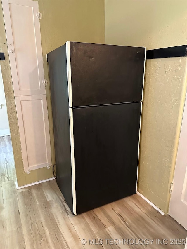 1927 N Cheyenne Ave, Tulsa, OK 74106 - kitchen view of freestanding refrigerator, light wood-type flooring, and a textured wall
