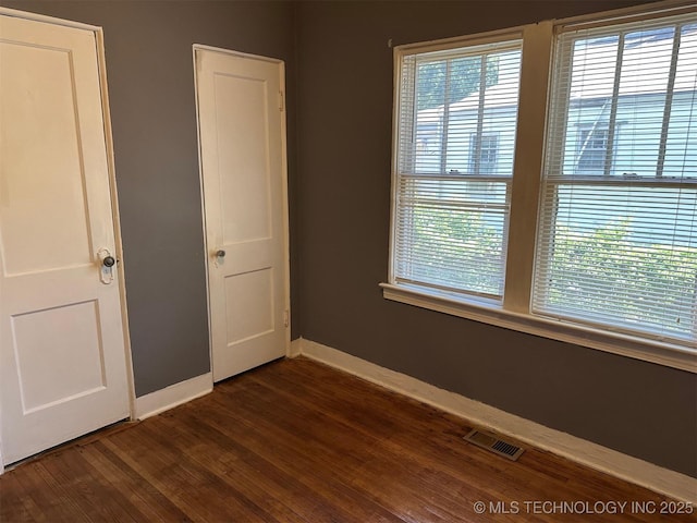 1927 N Cheyenne Ave, Tulsa, OK 74106 - unfurnished bedroom featuring multiple windows and dark wood-type flooring