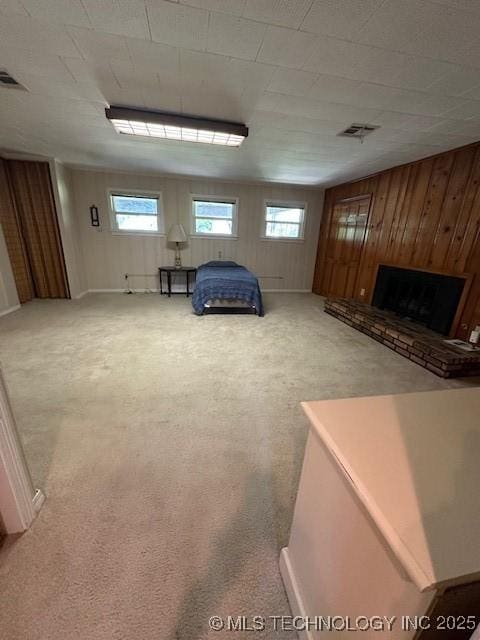 717 N Burns, Holdenville, OK 74848 - unfurnished bedroom featuring multiple windows, wooden walls, carpet, and a fireplace with raised hearth