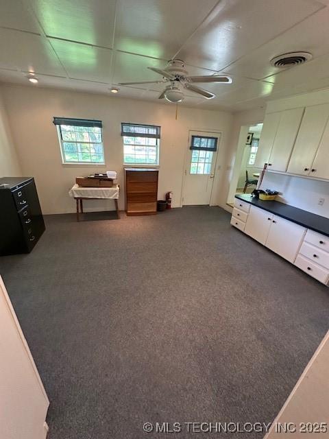 717 N Burns, Holdenville, OK 74848 - unfurnished living room with healthy amount of natural light, a ceiling fan, and dark carpet