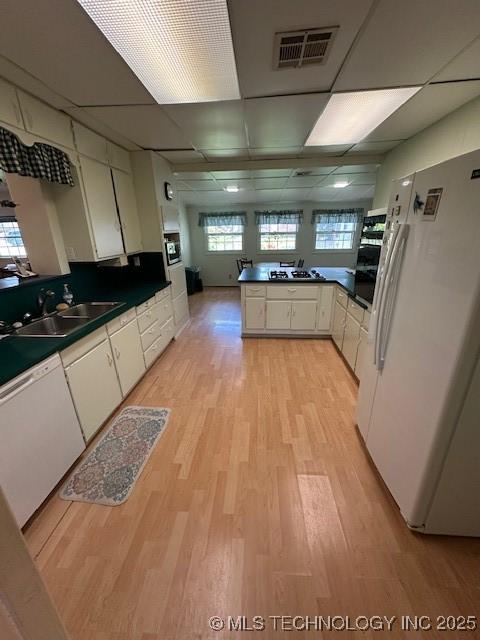 717 N Burns, Holdenville, OK 74848 - kitchen with white appliances, dark countertops, light wood-type flooring, a peninsula, and white cabinetry