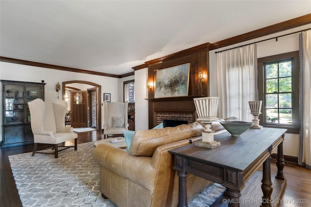 2404 S Woodward Blvd, Tulsa, OK 74114 - living room featuring arched walkways, wood finished floors, ornamental molding, and a brick fireplace
