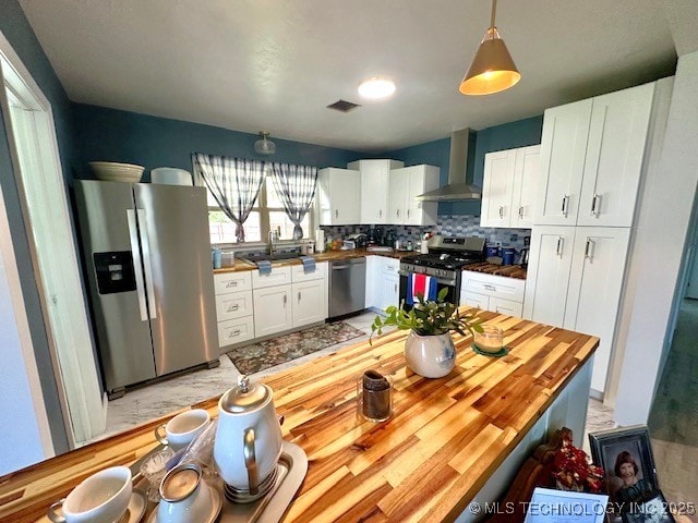 131 S Hyden, Stratford, OK 74872 - kitchen featuring appliances with stainless steel finishes, wall chimney range hood, white cabinets, decorative backsplash, and wood counters