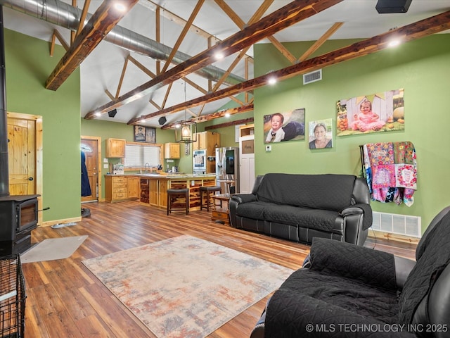 346 2570th Rd, Bartlesville, OK 74003 - living area with light wood-type flooring, high vaulted ceiling, a wood stove, and beam ceiling