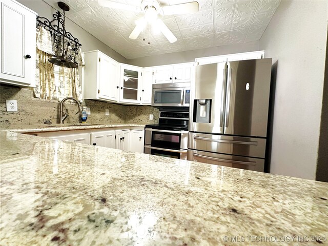 5371 Hilltop, Mcalester, OK 74501 - kitchen featuring appliances with stainless steel finishes, light stone counters, white cabinets, backsplash, and an ornate ceiling