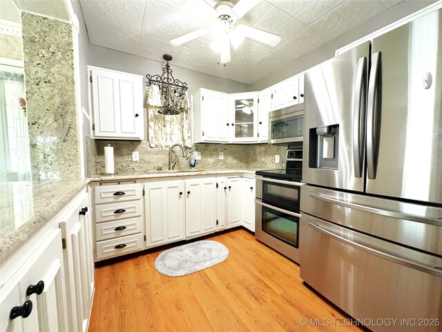 5371 Hilltop, Mcalester, OK 74501 - kitchen with stainless steel appliances, light wood-type flooring, tasteful backsplash, and white cabinetry