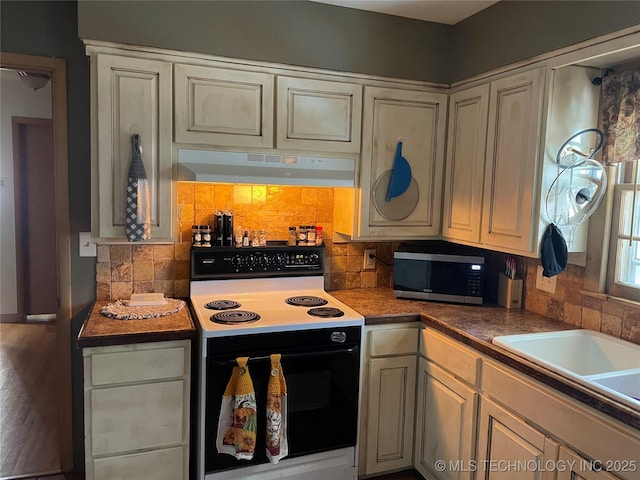 2509 Canterbury Ave, Muskogee, OK 74403 - kitchen with range with electric cooktop, stainless steel microwave, under cabinet range hood, and tasteful backsplash