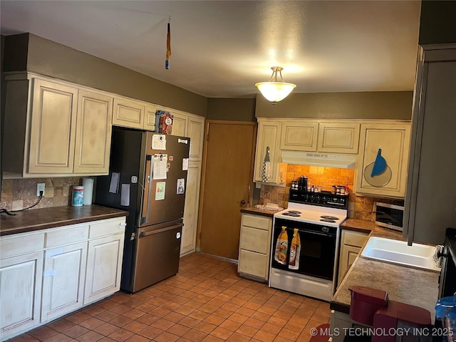 2509 Canterbury Ave, Muskogee, OK 74403 - kitchen with appliances with stainless steel finishes, under cabinet range hood, tasteful backsplash, and light tile patterned flooring