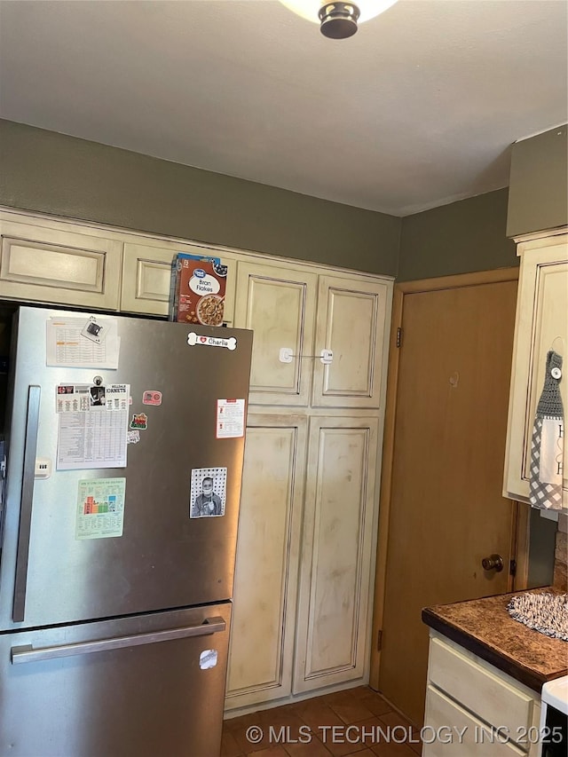 2509 Canterbury Ave, Muskogee, OK 74403 - kitchen with freestanding refrigerator, tile patterned floors, dark countertops, and cream cabinetry