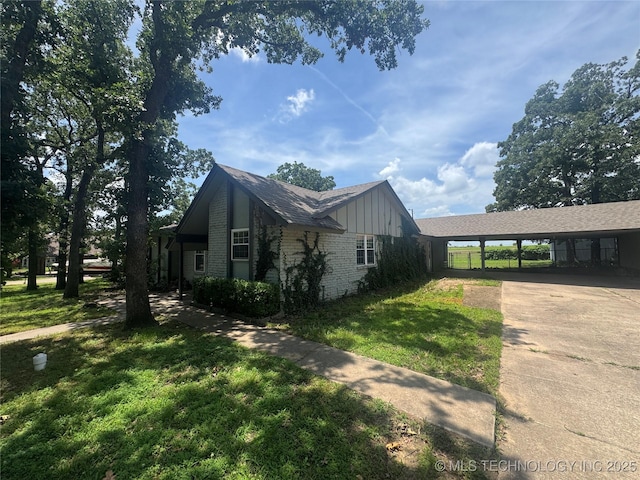 1516 Timber Ridge Dr, Cleveland, OK 74020 - view of property exterior with driveway, board and batten siding, a lawn, a carport, and brick siding