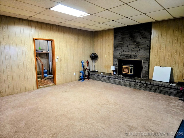 6850 E County Road 553, Kansas, OK 74347 - unfurnished living room with carpet floors, a paneled ceiling, a large fireplace, and wooden walls
