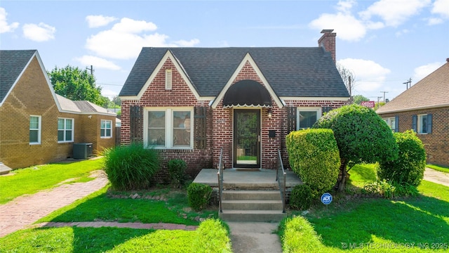 1516 S Lewis Pl, Tulsa, OK 74104 - tudor-style house featuring brick siding, a front yard, a chimney, and roof with shingles