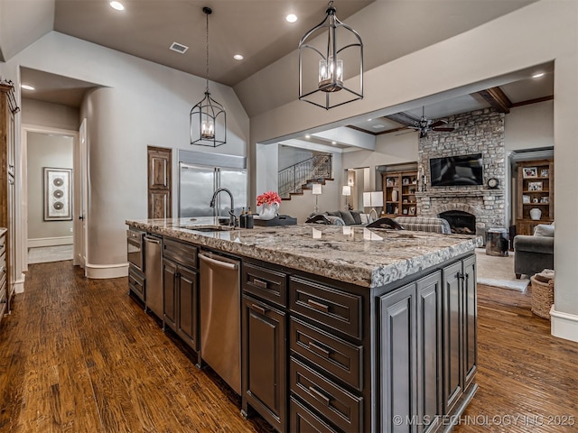 10741 S 93rd E Ave, Tulsa, OK 74133 - kitchen with a ceiling fan, appliances with stainless steel finishes, a stone fireplace, open floor plan, and a kitchen island with sink