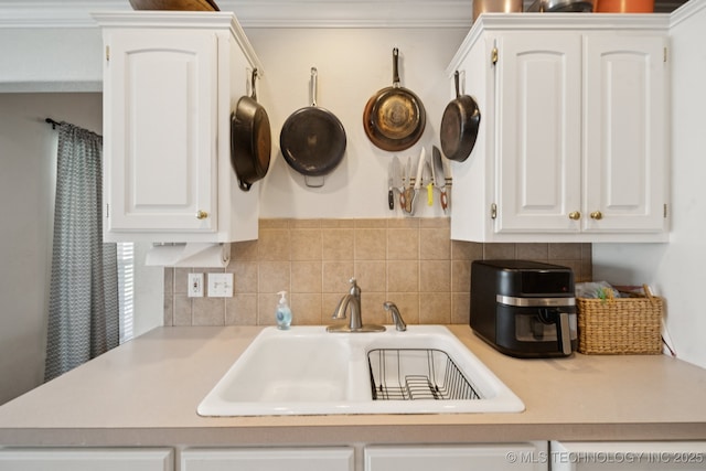 8931 E 62nd Pl, Tulsa, OK 74133 - kitchen with white cabinets, light countertops, backsplash, and crown molding