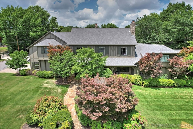 1111 E 24th Pl, Tulsa, OK 74114 - tudor home featuring a chimney, a front yard, and roof with shingles