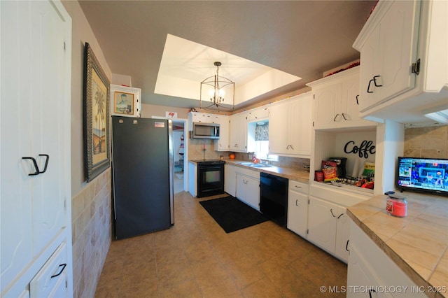 919 S 2nd St, Mcalester, OK 74501 - kitchen with black appliances, a tray ceiling, white cabinets, tile counters, and tasteful backsplash