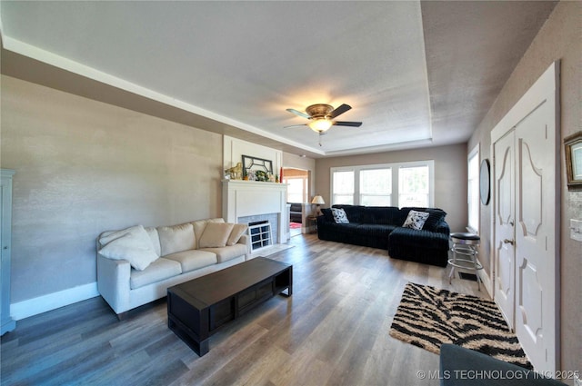 919 S 2nd St, Mcalester, OK 74501 - living area featuring wood finished floors, ceiling fan, a raised ceiling, and a fireplace with flush hearth