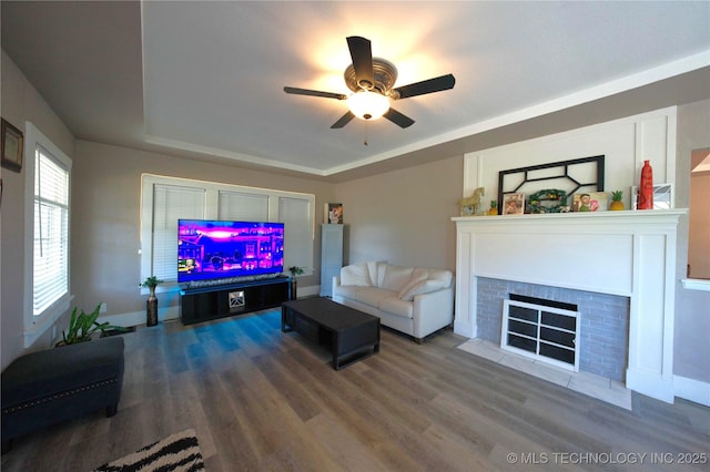 919 S 2nd St, Mcalester, OK 74501 - living area with a fireplace with flush hearth, a tray ceiling, wood finished floors, and a ceiling fan