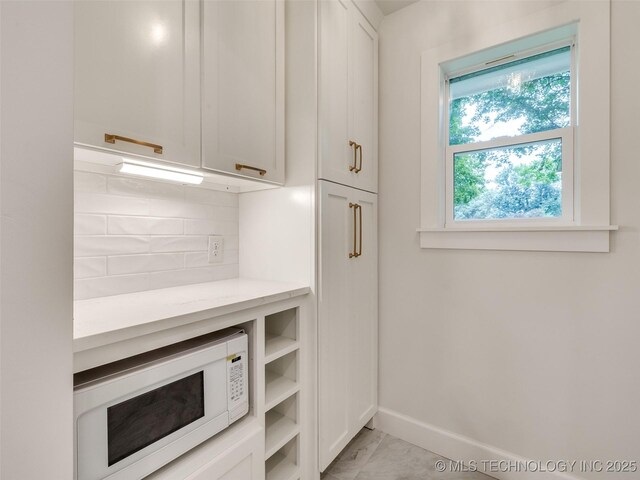 11702 S 75th E Ave, Bixby, OK 74008 - kitchen with white microwave, tasteful backsplash, white cabinets, and light marble finish floors