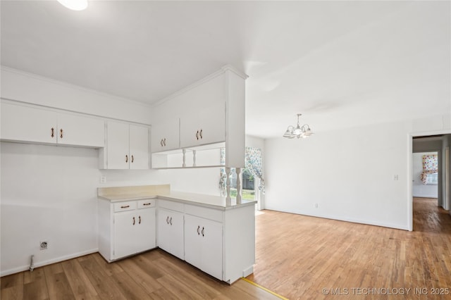 503 N Prairie Ave, Okmulgee, OK 74447 - kitchen with a chandelier, light countertops, light wood finished floors, white cabinets, and open floor plan