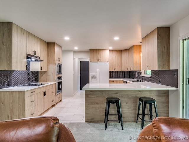 701 W 41st St, Sand Springs, OK 74063 - kitchen with black appliances, light brown cabinetry, a peninsula, a breakfast bar, and light countertops