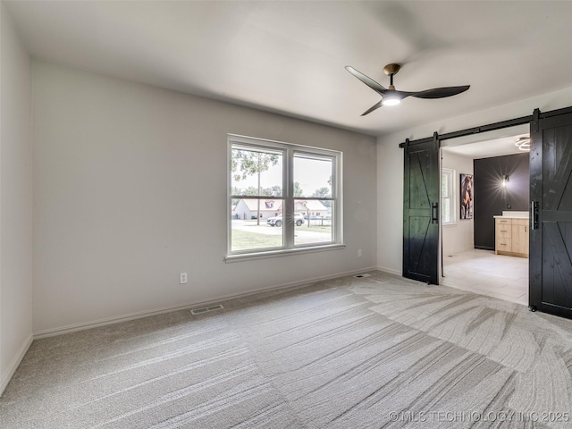 701 W 41st St, Sand Springs, OK 74063 - unfurnished bedroom featuring a barn door, light carpet, and ceiling fan