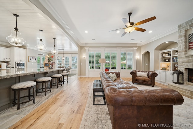 6140 E 140th St S, Bixby, OK 74008 - living area featuring a ceiling fan, a stone fireplace, ornamental molding, built in features, and light wood-type flooring