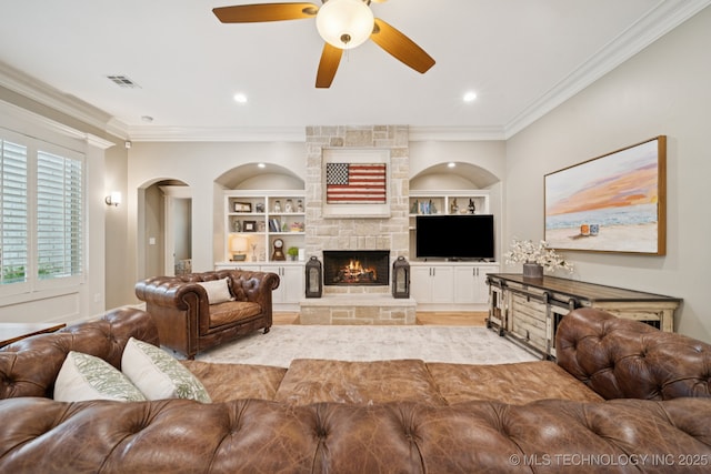 6140 E 140th St S, Bixby, OK 74008 - living area featuring ceiling fan, crown molding, built in shelves, a stone fireplace, and arched walkways