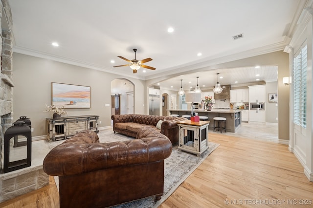 6140 E 140th St S, Bixby, OK 74008 - living area featuring arched walkways, a stone fireplace, a ceiling fan, recessed lighting, and light wood-style flooring