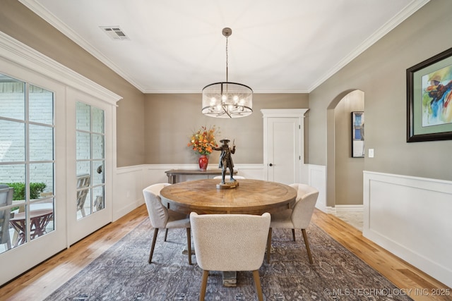 6140 E 140th St S, Bixby, OK 74008 - dining room with light wood-style floors, arched walkways, a chandelier, a wainscoted wall, and crown molding