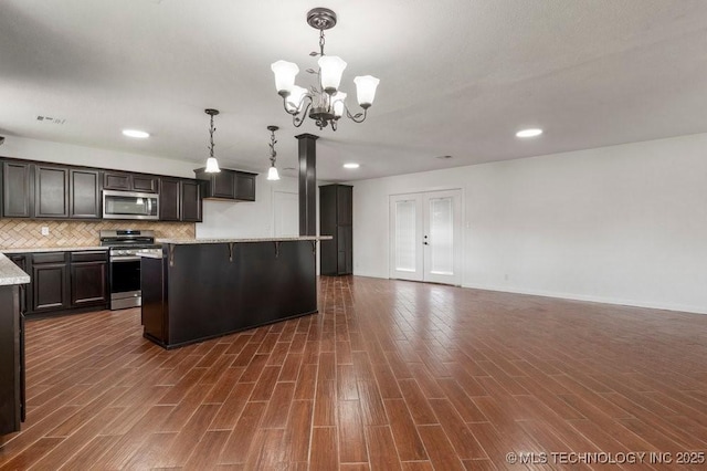 1706 S Madison Blvd, Bartlesville, OK 74006 - kitchen featuring stainless steel appliances, a chandelier, dark wood finished floors, backsplash, and pendant lighting