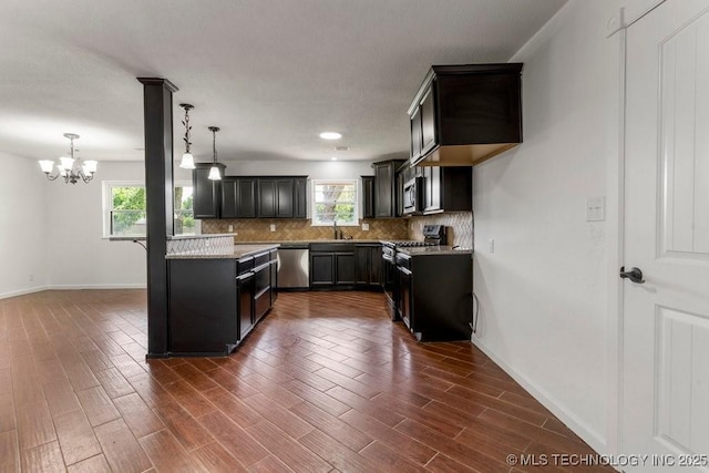 1706 S Madison Blvd, Bartlesville, OK 74006 - kitchen featuring stainless steel appliances, tasteful backsplash, dark wood finished floors, a chandelier, and hanging light fixtures