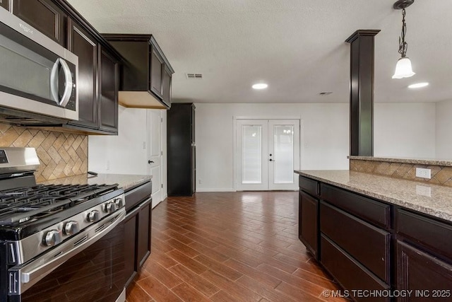 1706 S Madison Blvd, Bartlesville, OK 74006 - kitchen featuring stainless steel appliances, backsplash, light stone countertops, dark brown cabinetry, and hanging light fixtures