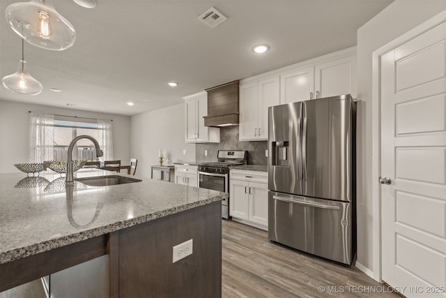 13009 E 124th Ct, Collinsville, OK 74021 - kitchen with stainless steel appliances, premium range hood, white cabinets, a breakfast bar, and light wood finished floors