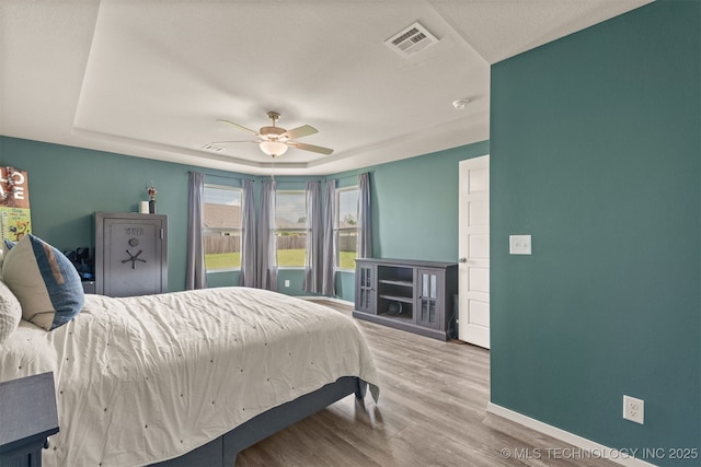 13009 E 124th Ct, Collinsville, OK 74021 - bedroom with wood finished floors, ceiling fan, and a tray ceiling
