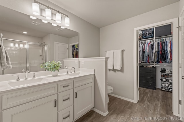 13009 E 124th Ct, Collinsville, OK 74021 - bathroom featuring wood finished floors, double vanity, a walk in closet, and a shower stall