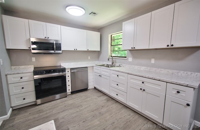 1619 Quail Run, Muskogee, OK 74403 - kitchen with appliances with stainless steel finishes, light wood-type flooring, white cabinetry, and light stone counters