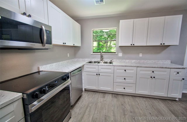 1619 Quail Run, Muskogee, OK 74403 - kitchen with stainless steel appliances, light wood-type flooring, white cabinetry, and light stone counters