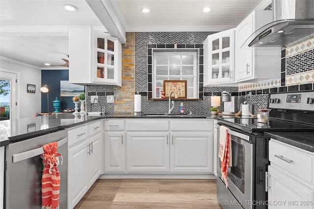 96164 S Strayhorn Heights Rd, Gore, OK 74435 - kitchen featuring appliances with stainless steel finishes, wall chimney exhaust hood, crown molding, white cabinets, and light wood-type flooring