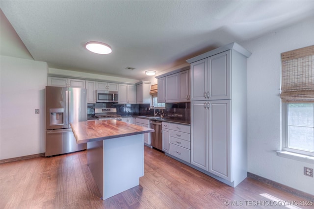 17542 W 1st St S, Sand Springs, OK 74063 - kitchen with stainless steel appliances, gray cabinetry, tasteful backsplash, wood finished floors, and a center island