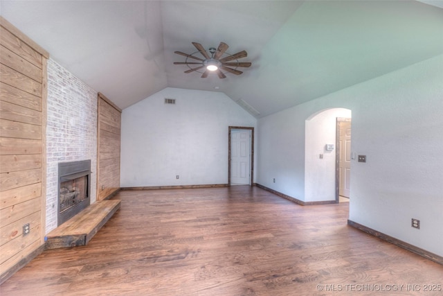 17542 W 1st St S, Sand Springs, OK 74063 - unfurnished living room with a ceiling fan, arched walkways, vaulted ceiling, wood finished floors, and a large fireplace