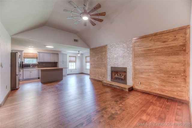 17542 W 1st St S, Sand Springs, OK 74063 - unfurnished living room with a ceiling fan, light wood-style floors, vaulted ceiling, and a large fireplace